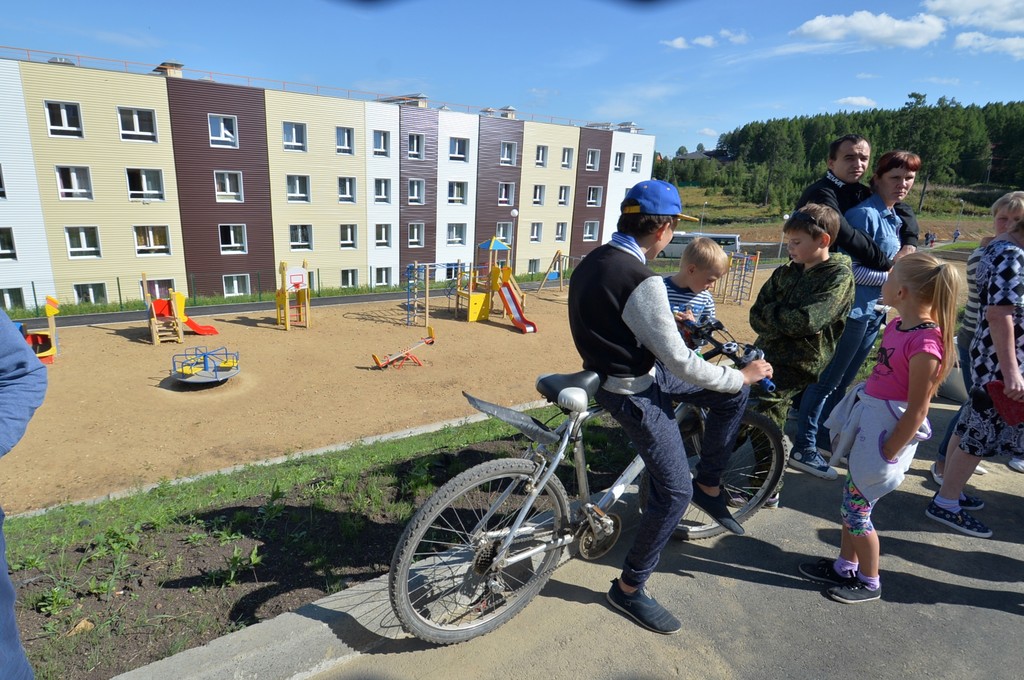 Дети с велосипедом на детской площадке у новостроек в Дегтярске