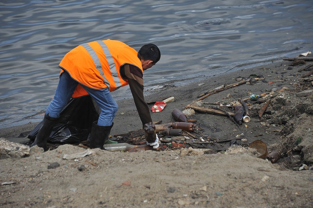 В числе предметов, которые приходится убирать с берега, — бутылки, металлические предметы  и небольшие брёвна. Фото: Павел Ворожцов