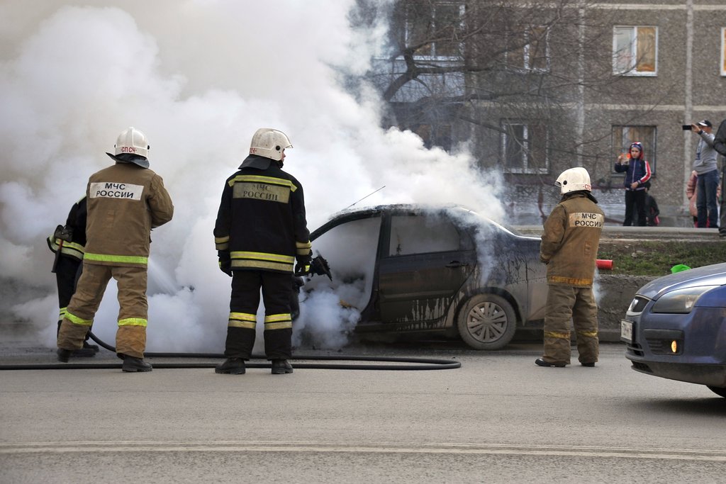 Спасатели тушат загоревшийся автомобиль.