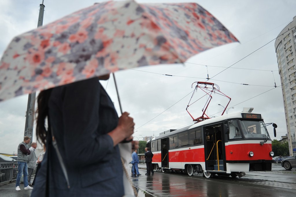 женщина под зонтом на фоне трамвае