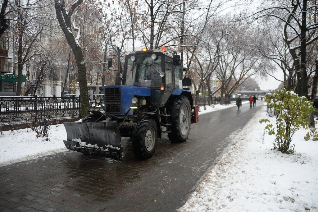 трактор чистит тротуар от снега