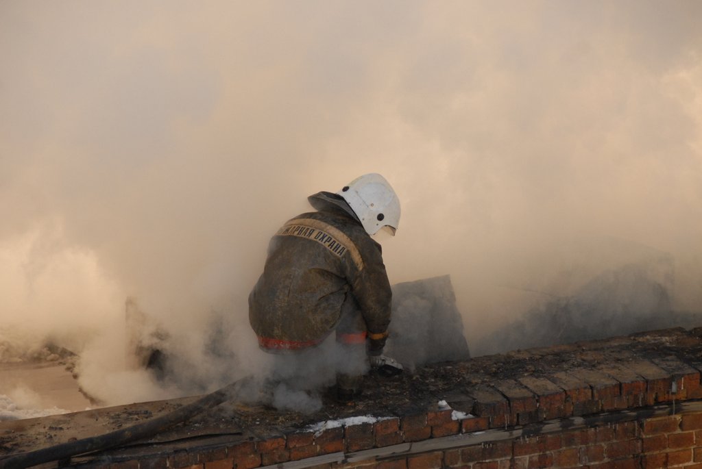 Спасатель тушит пожар на крыше