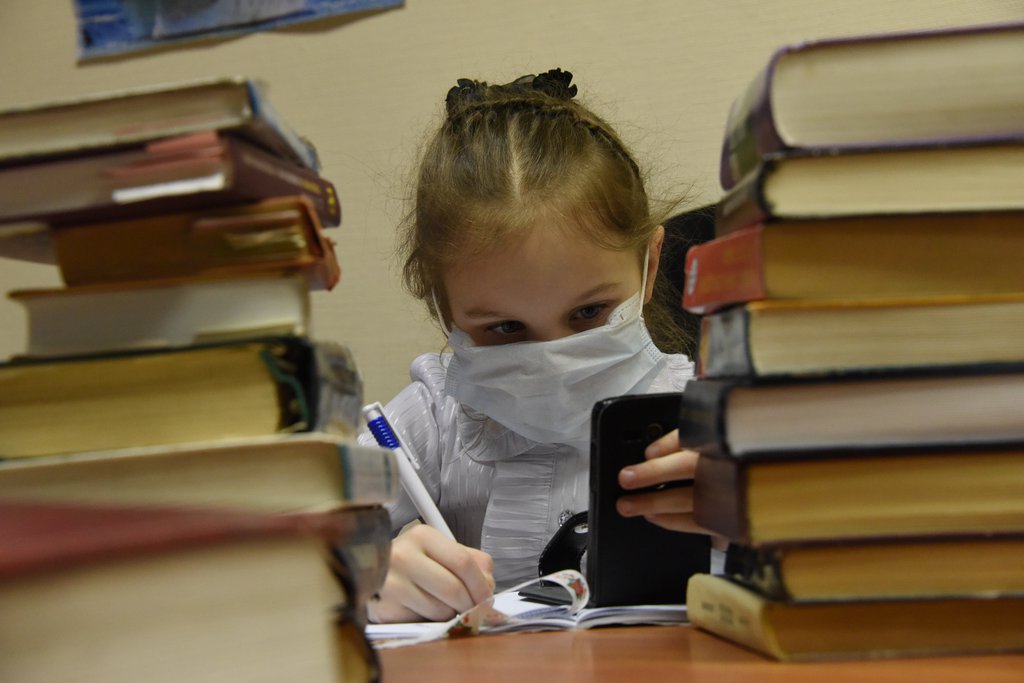 Девочка в медицинской маске делает уроки