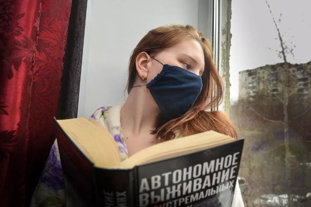 Девушка в маске читает дома