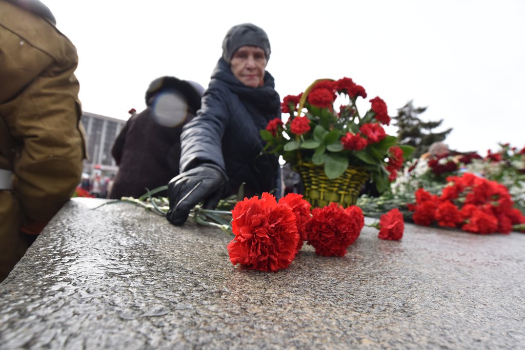 женщина возлагает цветы к памятнику