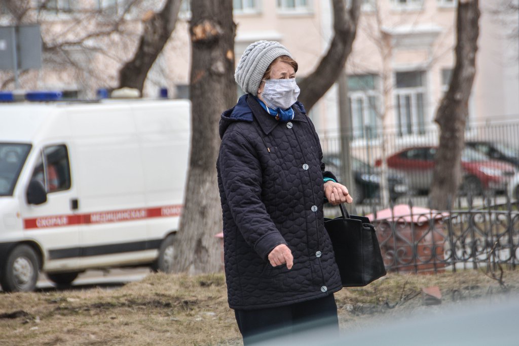 Женщина в маске идёт по улице