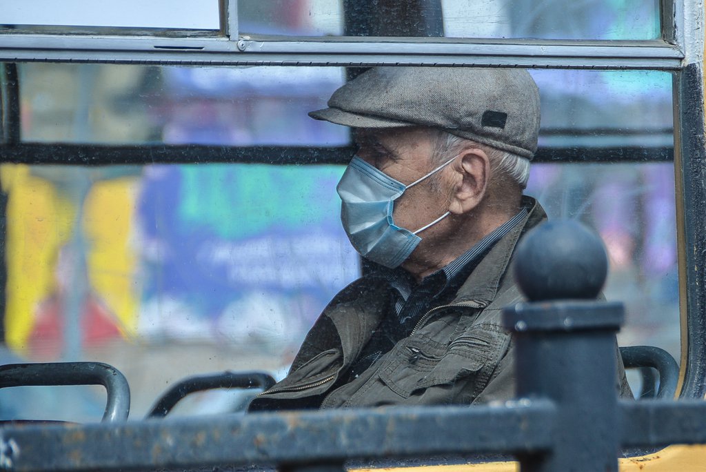 Пенсионер в маске едет в общественном транспорте