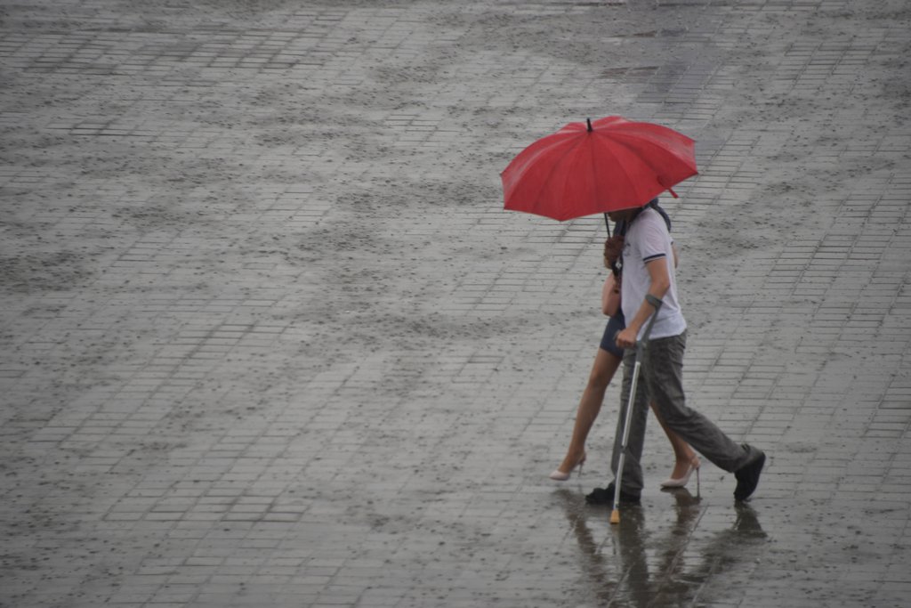 Мужчина и женщина идут под красным зонтом