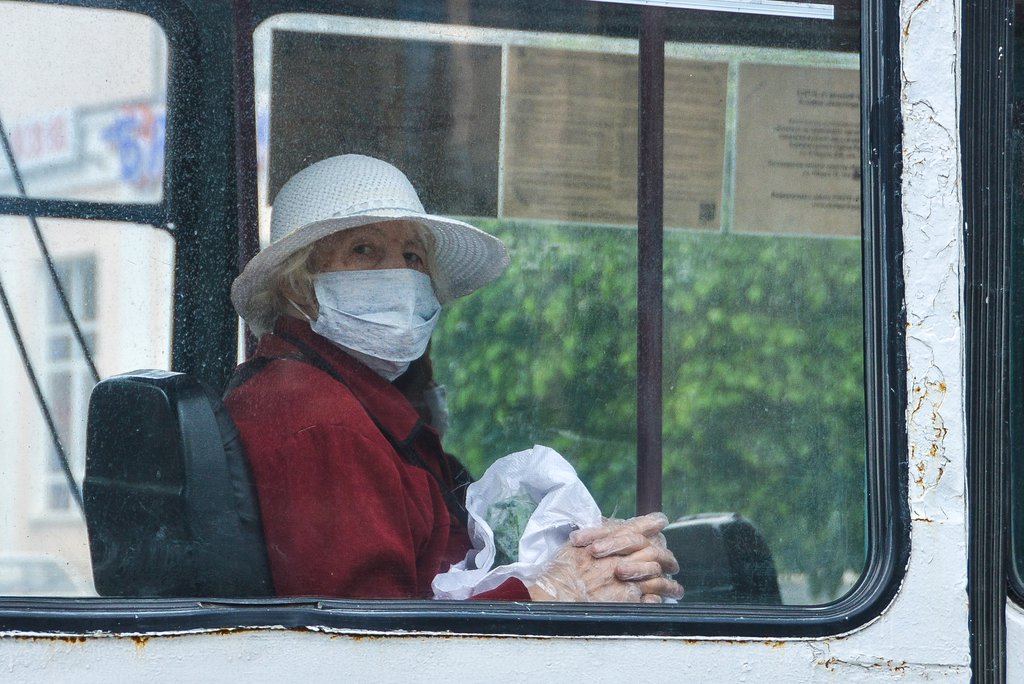 Пенсионерка в маске и перчатках едет в автобусе