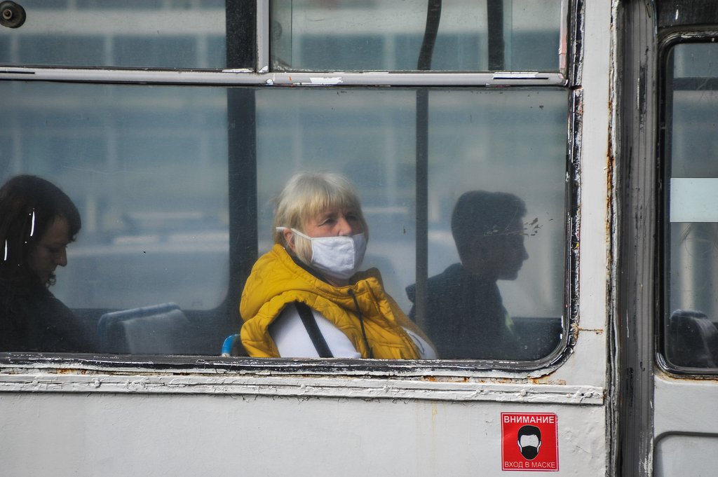 Женщина в маске едет в автобусе
