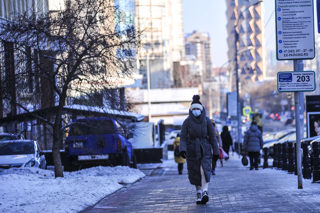 Женщина идёт по улице в маске зимой