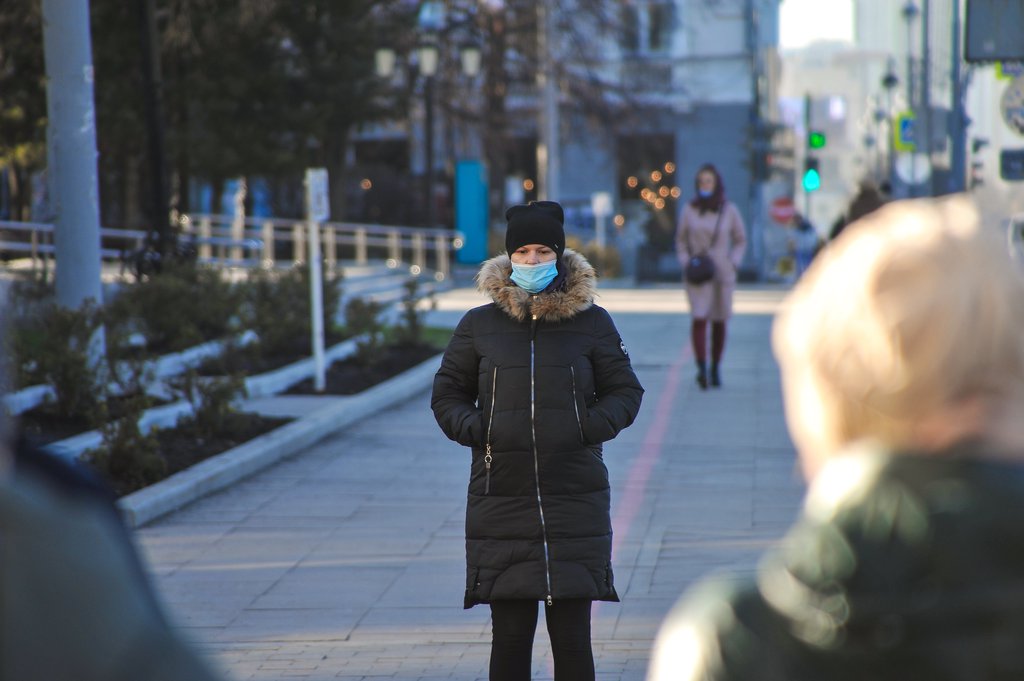 Девушка в маске идёт зимой по городу
