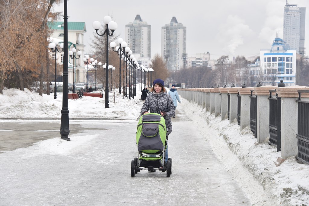 Девушка с коляской идёт по улице зимой