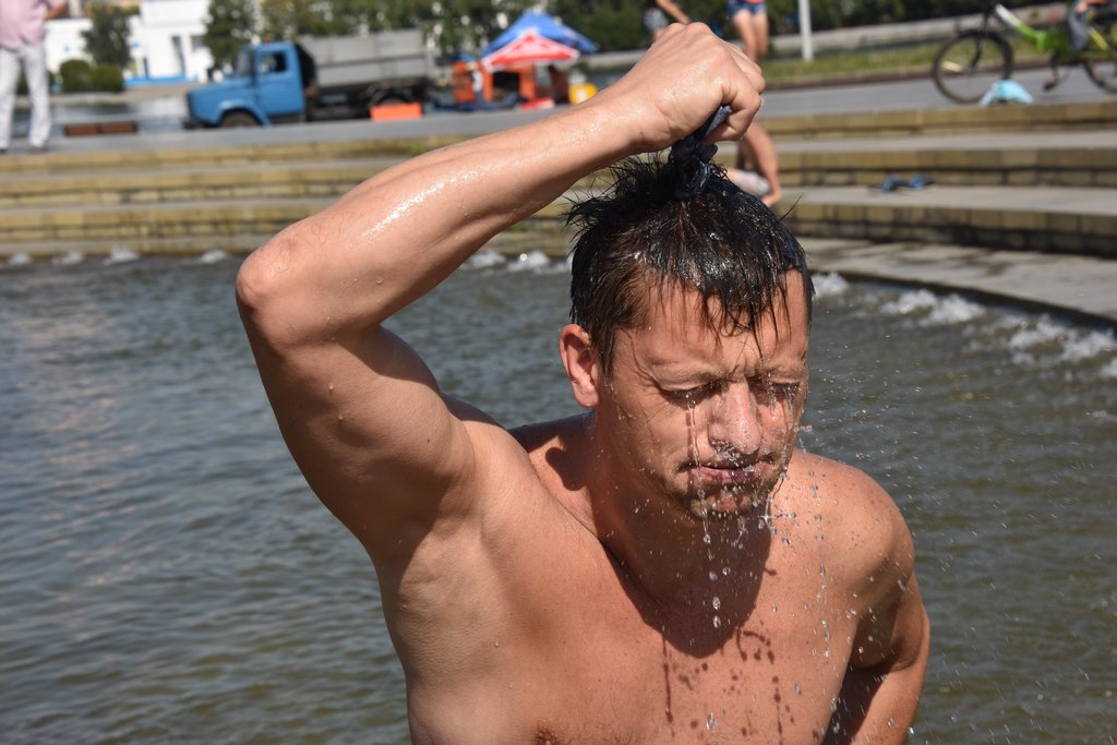 Мужчина обливается водой в жару