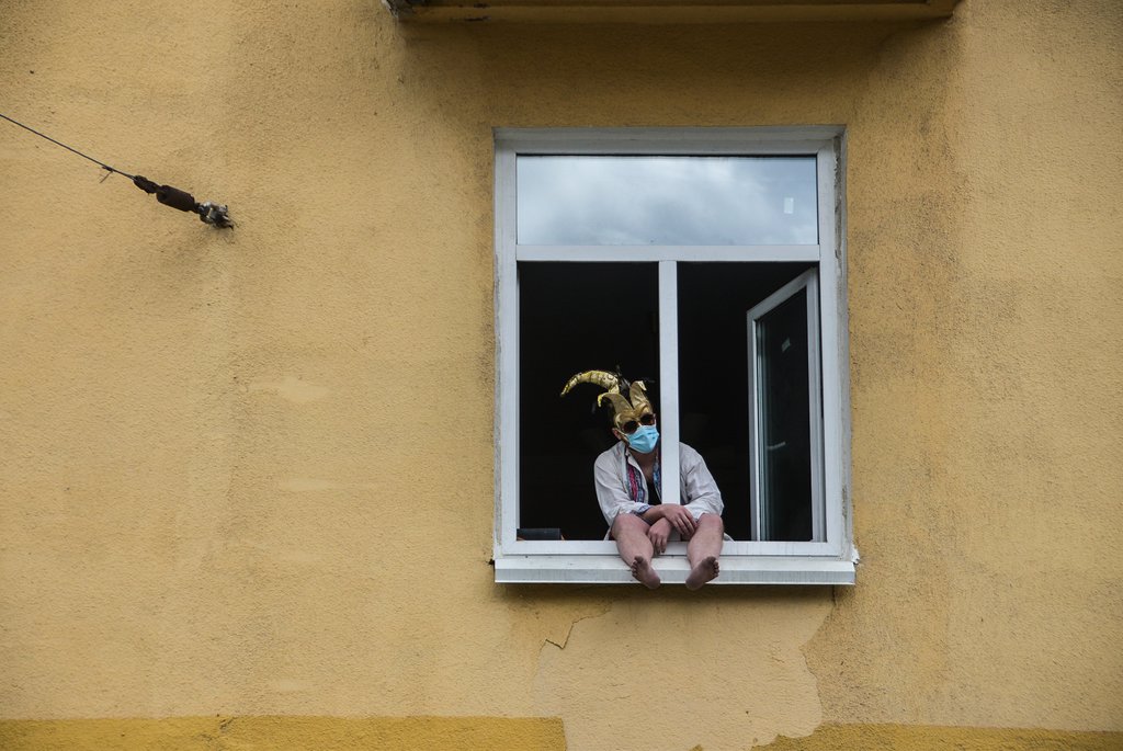 Мужчина в маске сидит на окне