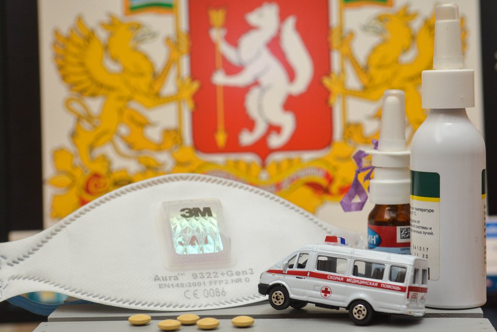 Таблетки и машинка скорой помощи на фоне герба региона