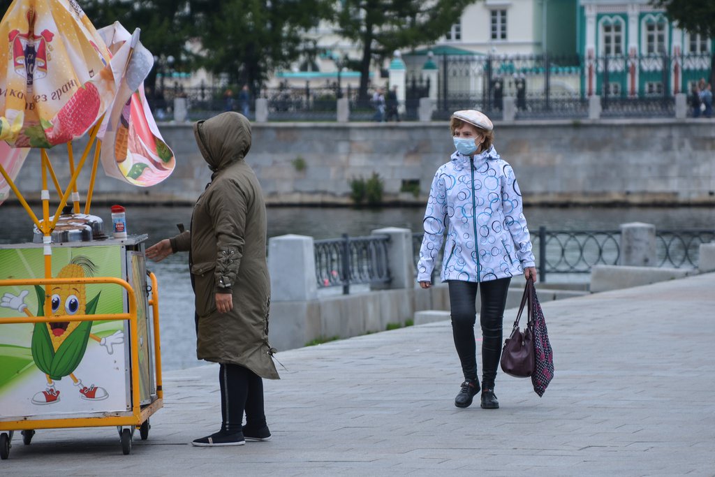 Женщина в маске идёт вдоль набережной