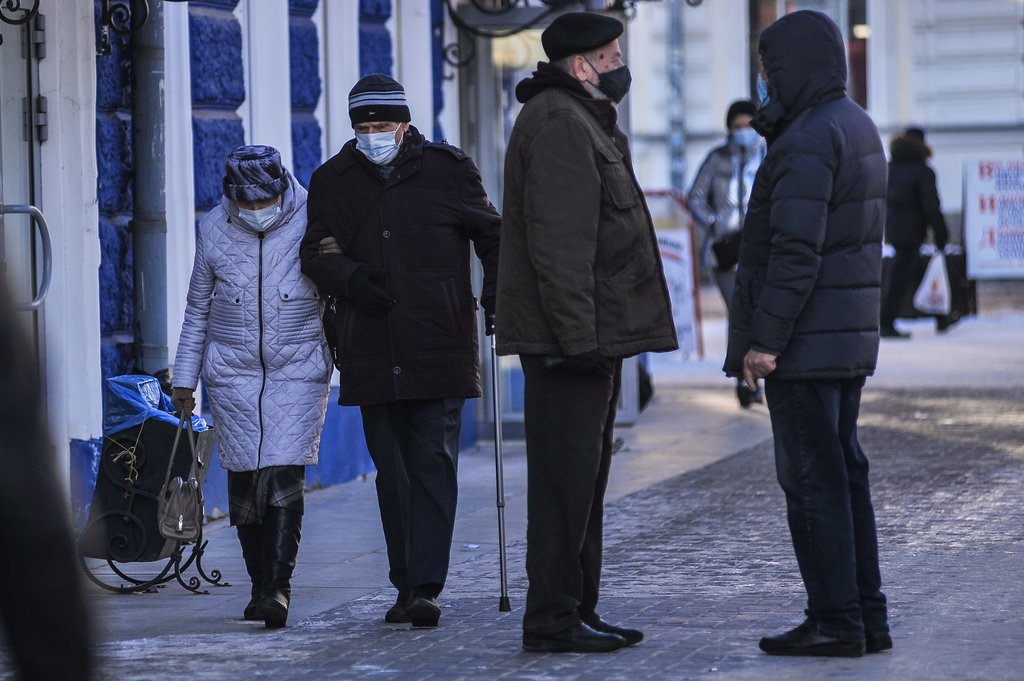 Люди в масках идут по улице зимой