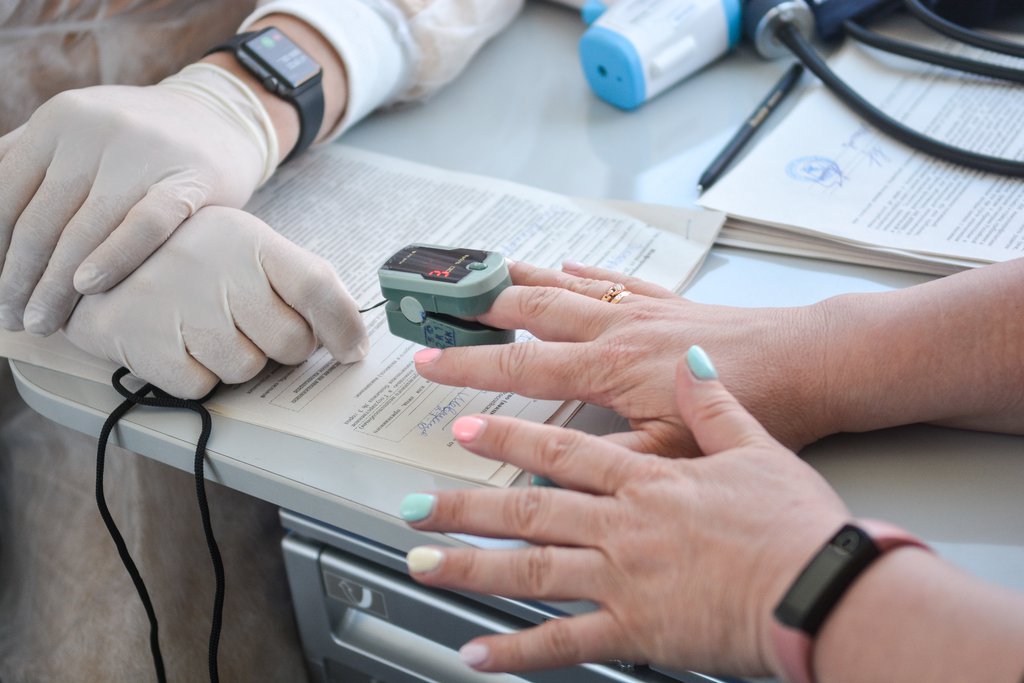 Врач измеряет уровень кислорода в крови у пациента