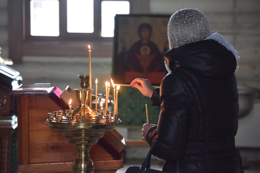 Женщина ставит свечи в церкви