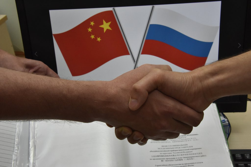 Рукопожатие на фоне флагов России и Китая