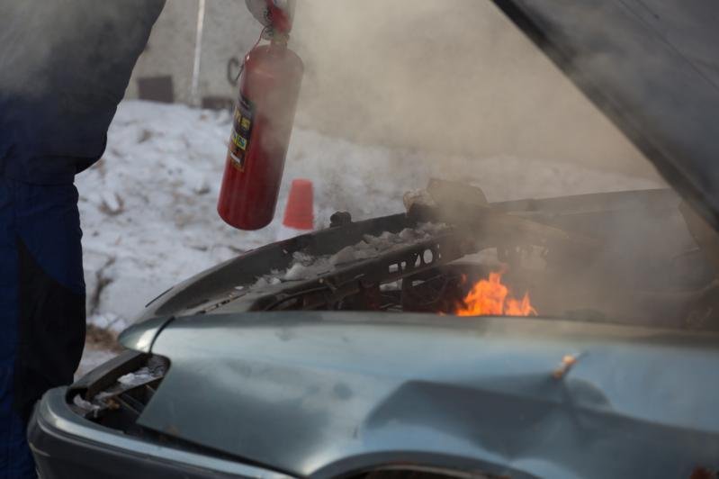 Спасатель тушит загоревшийся автомобиль