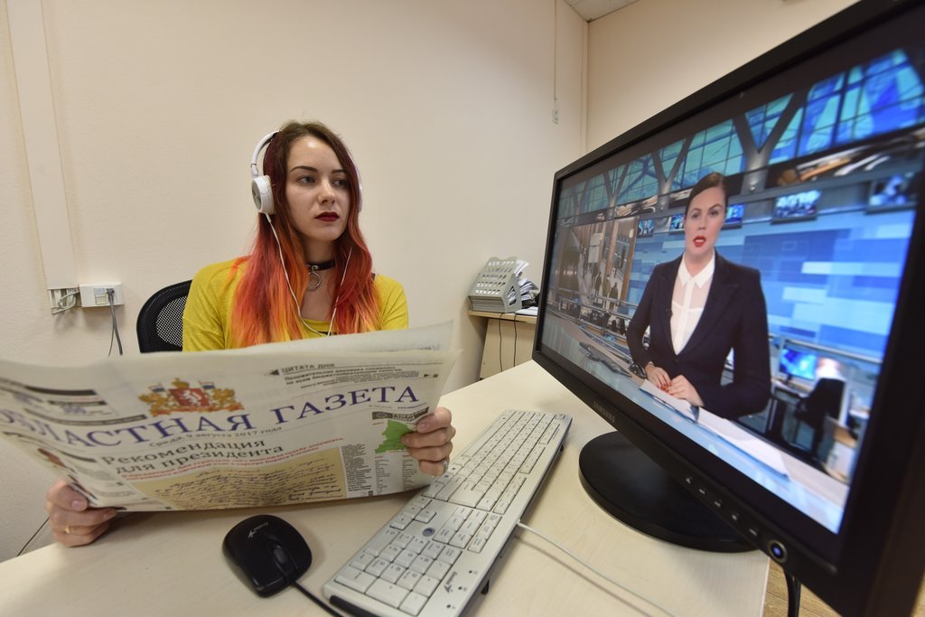 Девушка смотрит новости и листает газету
